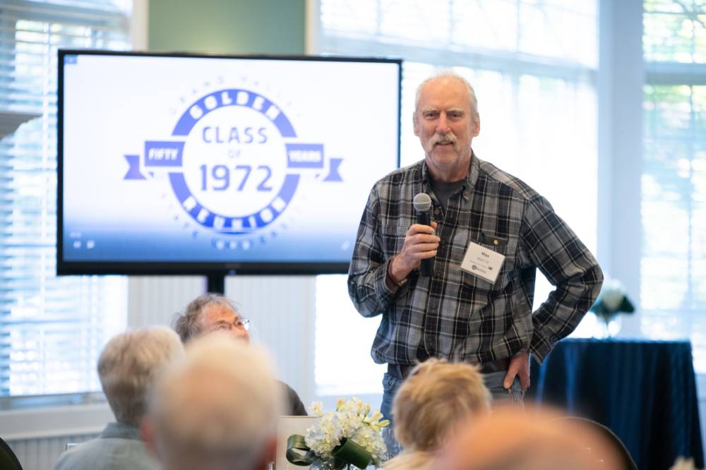 An alumni standing up speaking to the audience.